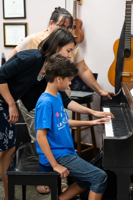 Piano student gets a lesson on using the left hand.